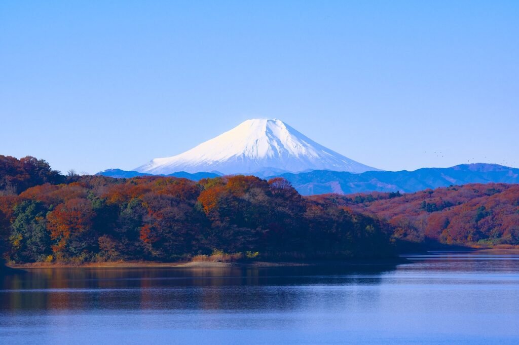 Mount Fuji viewed from Sayama Lake, with clear skies, autumn leaves, and the surrounding Sayama Hills. A serene natural landscape near Tokyo showcasing the iconic Fuji-san in crisp winter light.