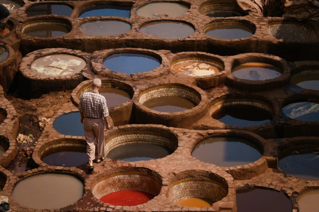 A worker in the traditional tannery of Fes, Morocco, surrounded by colorful dye pits.