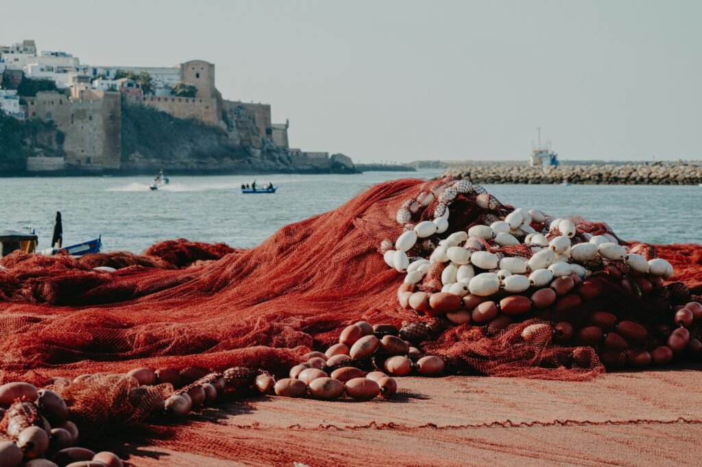 Vibrant fishing nets on the shore with a historical fortress in Rabat, Morocco, a blend of tradition and scenery.