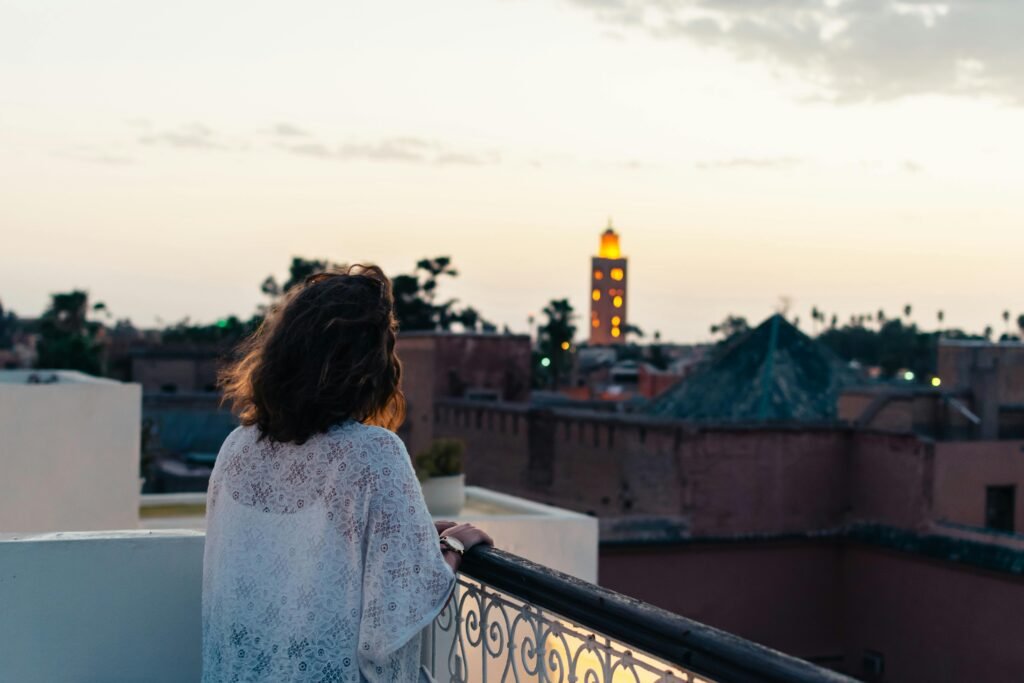 A woman gazes at the evening skyline of Marrakech, appreciating the sunset from her hotel balcony.