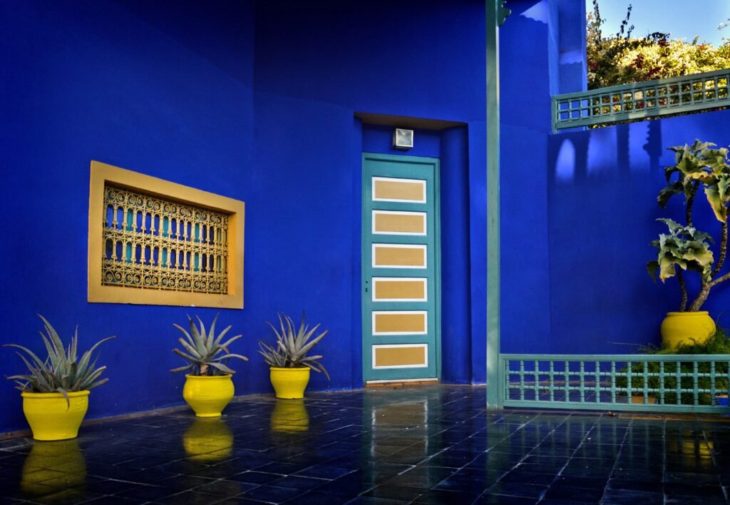 Colorful Moroccan courtyard with blue walls and yellow planters in Marrakech.