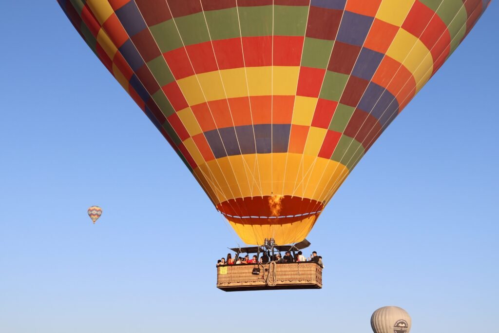 Colorful hot air balloons floating in Cappadocia's clear blue sky, offering a scenic aerial adventure.