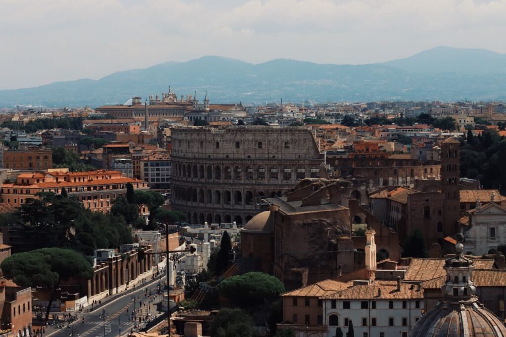 Drone shot of the iconic Colosseum and surrounding cityscape in Rome, Italy.