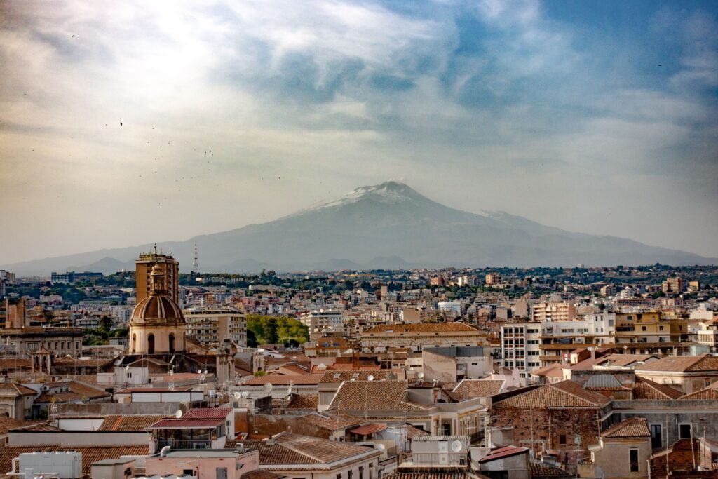 A breathtaking cityscape of Catania, Sicily with Mount Etna in the background, showcasing urban and natural beauty.