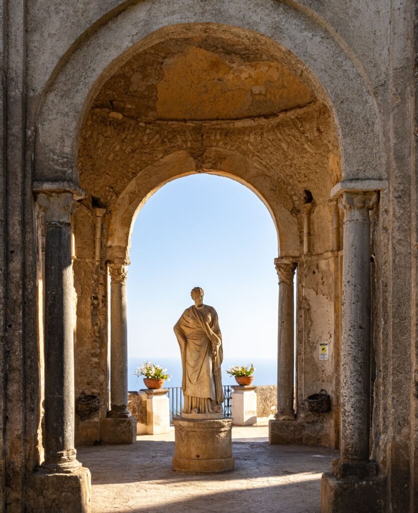Elegant Roman statue under arches at Villa Cimbrone, Italy, overlooking the sea.