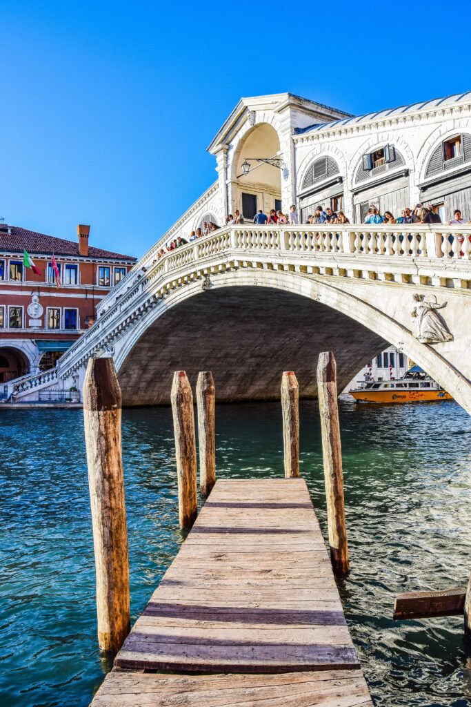 Iconic view of Rialto Bridge over Grand Canal in Venice, featuring vibrant architecture.