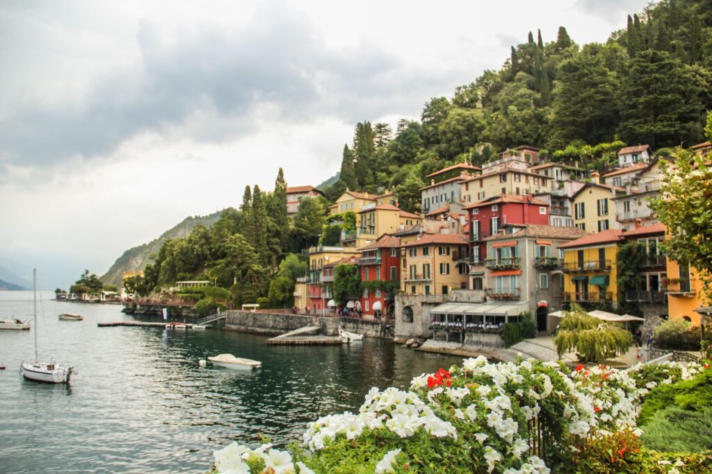 Picturesque Varenna village at Lake Como with colorful houses and sailboats against lush hills.
