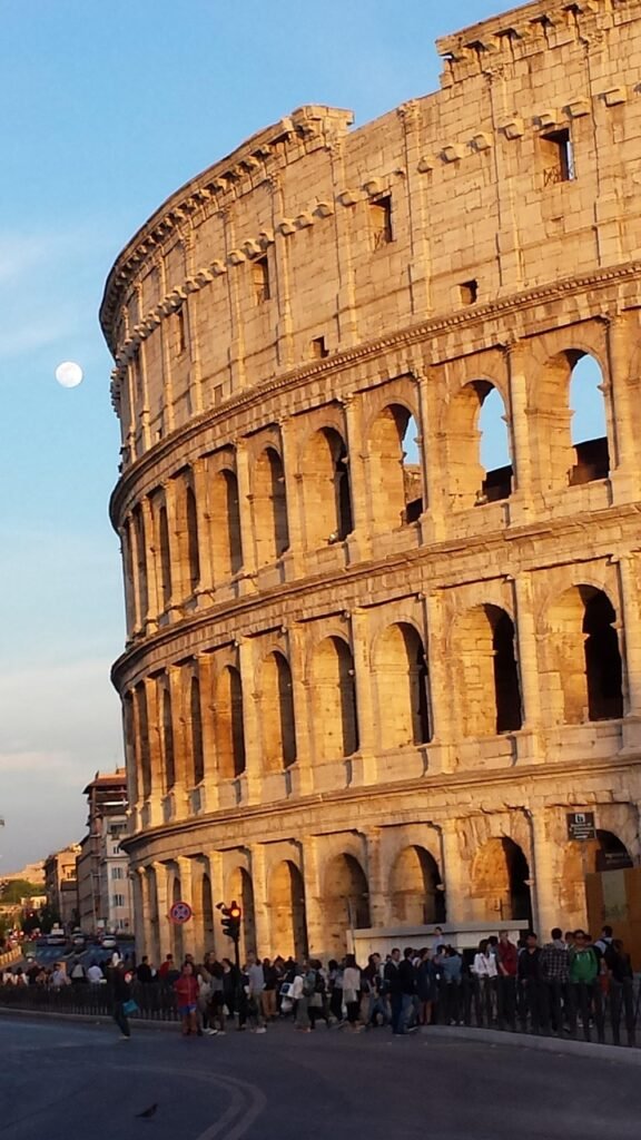 Colosseum in Rome illuminated under a full moon at evening, Italy