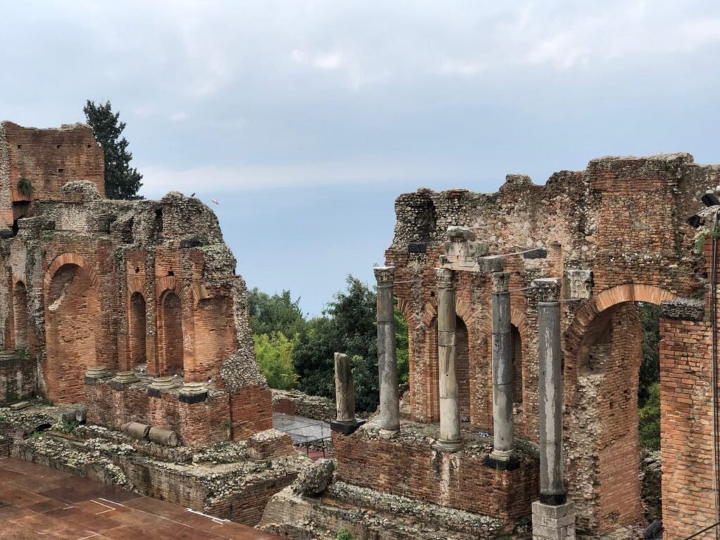 Explore the historic ruins of the Greek Theater in Taormina, Sicily, featuring ancient architecture and stunning views.