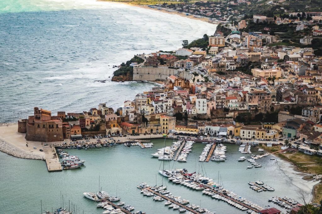 A picturesque aerial shot of a coastal town in Sicily, showcasing the marina and historic architecture.