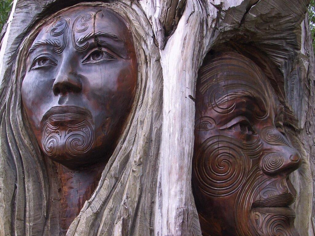 Traditional Māori wood carving featuring carved human figures and faces in New Zealand.