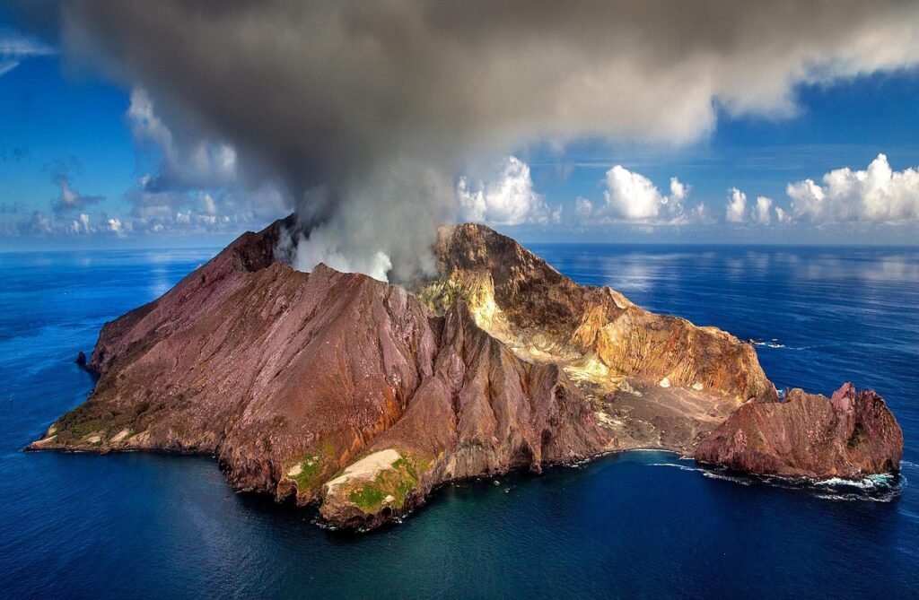 Aerial view of Whakaari (White Island), an active volcanic island in New Zealand’s Bay of Plenty, with smoke rising from its crater.