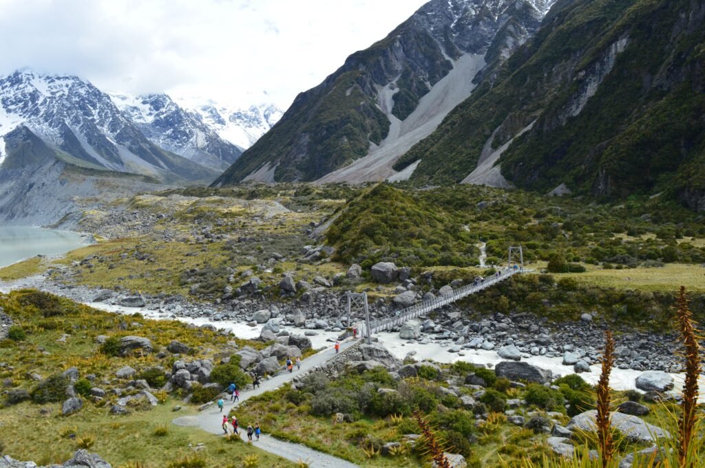 Hikers traverse a scenic bridge in Aoraki / Mount Cook, New Zealand.