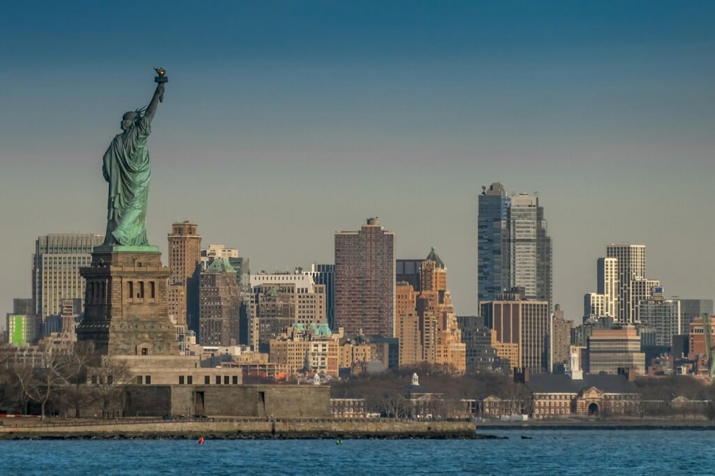 Side picture of Statue of liberty overlooking new york city's skyline. 
